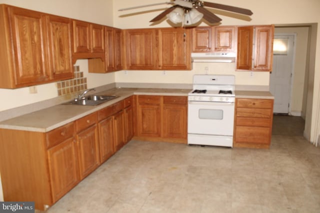 kitchen featuring a ceiling fan, a sink, light countertops, white gas range oven, and under cabinet range hood