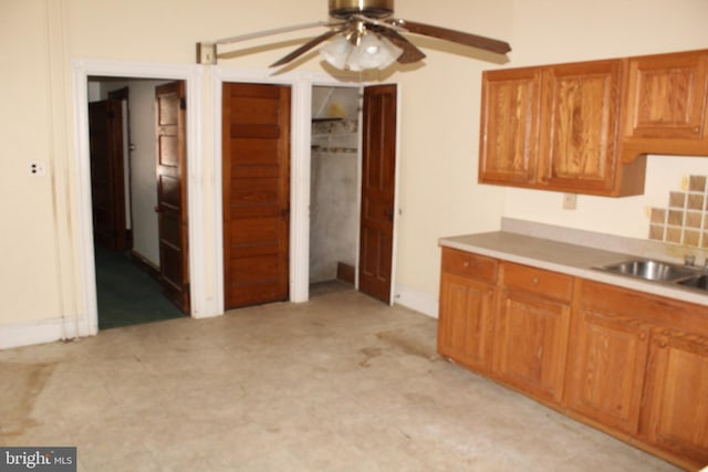 kitchen featuring brown cabinets, ceiling fan, a sink, light countertops, and light floors