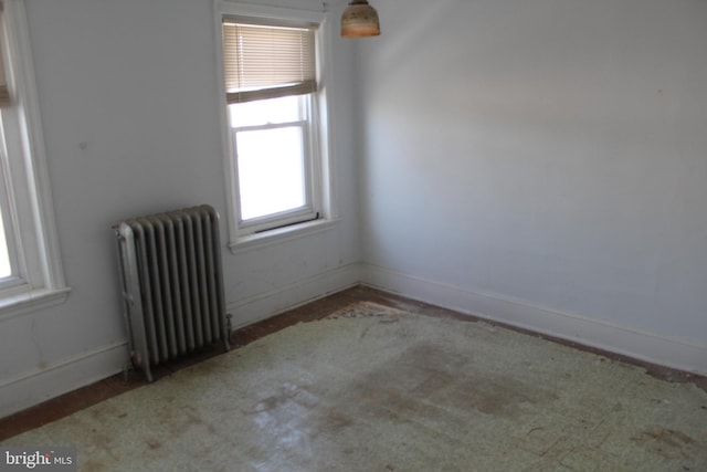 empty room featuring baseboards, a wealth of natural light, and radiator