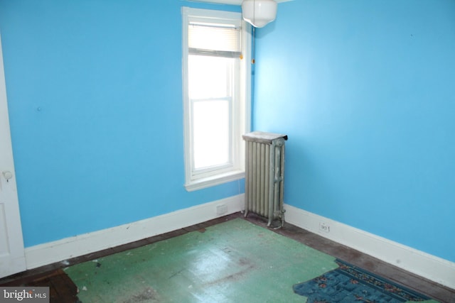 unfurnished room with baseboards, radiator, and plenty of natural light