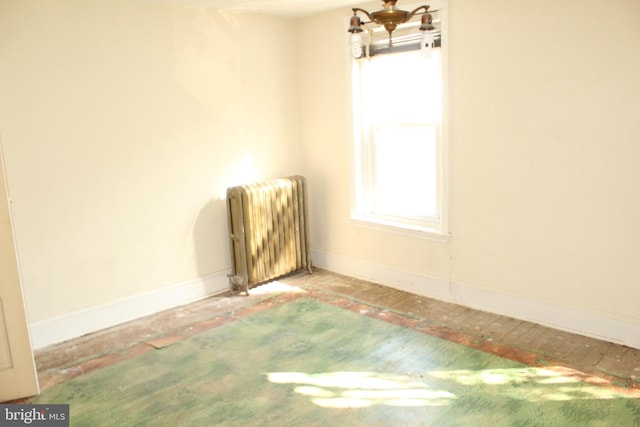 spare room with radiator, baseboards, and a chandelier