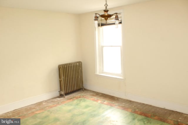 empty room featuring radiator heating unit, baseboards, and plenty of natural light