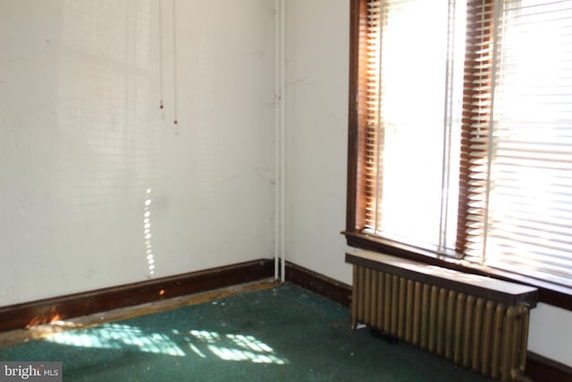 unfurnished room featuring radiator heating unit and baseboards