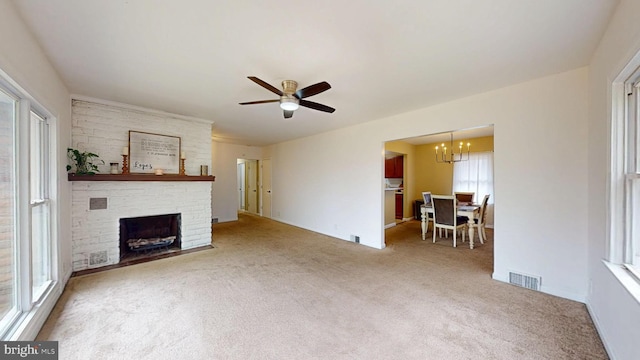 carpeted living area with a fireplace, visible vents, and ceiling fan with notable chandelier
