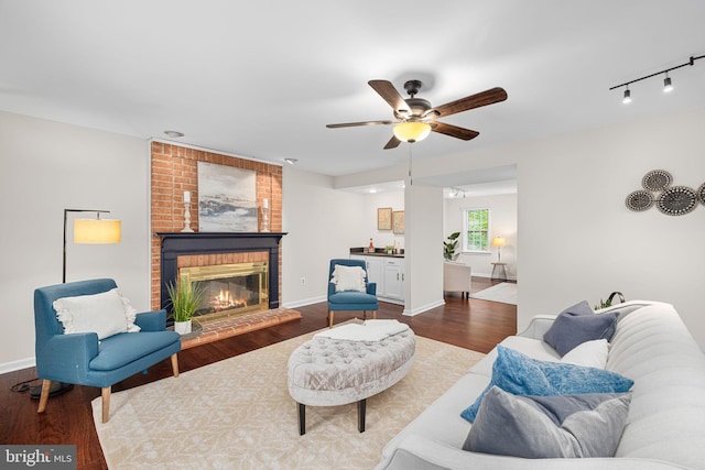 1517 Snughill Ct, Vienna, VA 22182 - living area with ceiling fan, dark wood-style flooring, a brick fireplace, rail lighting, and baseboards