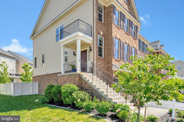 view of front of house with brick siding and a balcony