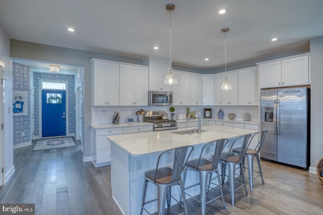kitchen featuring stainless steel appliances, wood finished floors, a sink, and white cabinetry