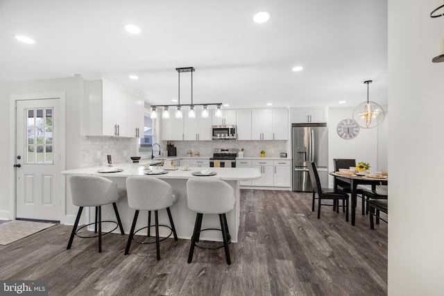 kitchen with a peninsula, white cabinetry, stainless steel appliances, and a sink