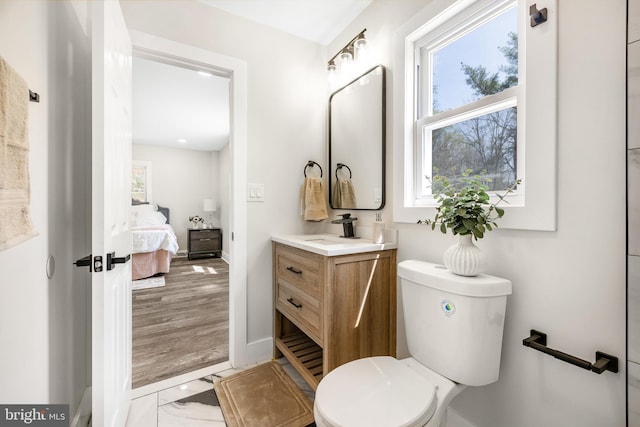 ensuite bathroom featuring baseboards, connected bathroom, vanity, and toilet