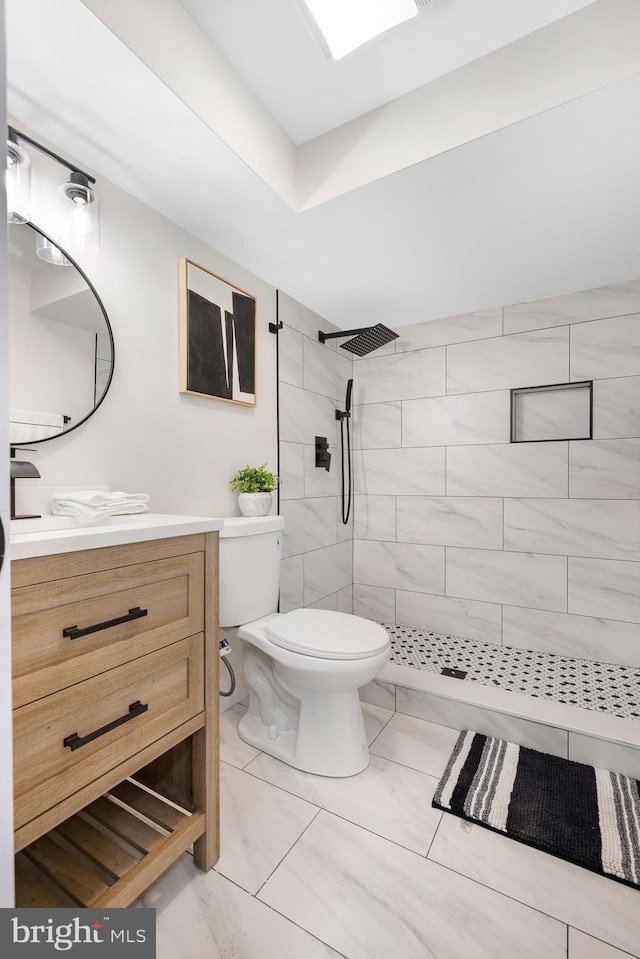 bathroom with vanity, toilet, and tiled shower