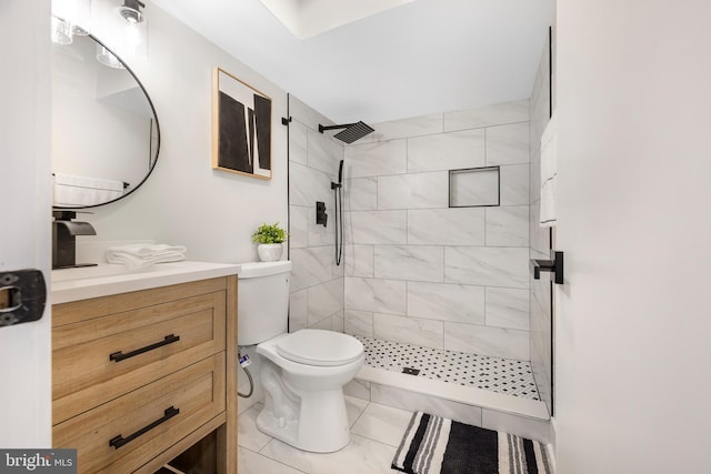 full bathroom with a tile shower, toilet, and vanity