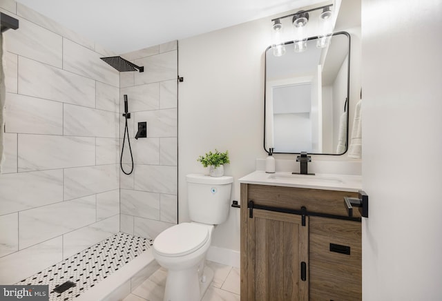 bathroom featuring baseboards, toilet, vanity, and tiled shower