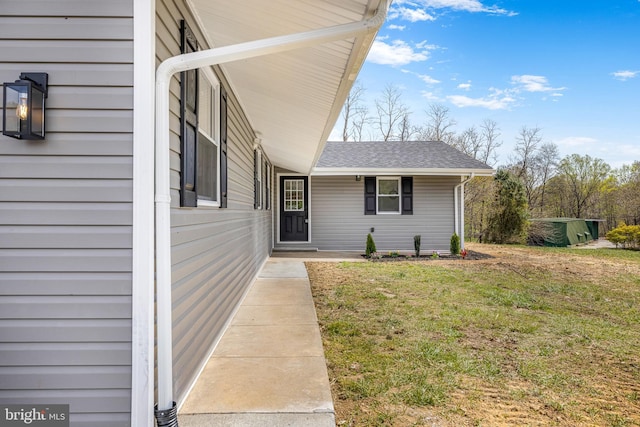property entrance with roof with shingles and a yard