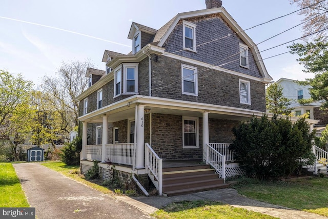 610 Washington Ln, Jenkintown, PA 19046 - view of front of property with a storage shed, a chimney, stone siding, an outbuilding, and a porch
