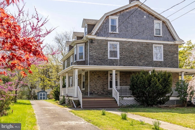 610 Washington Ln, Jenkintown, PA 19046 - view of front of house featuring a front lawn, an outbuilding, covered porch, a storage unit, and roof with shingles