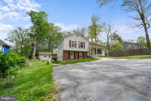 split level home with brick siding, fence, aphalt driveway, and a porch