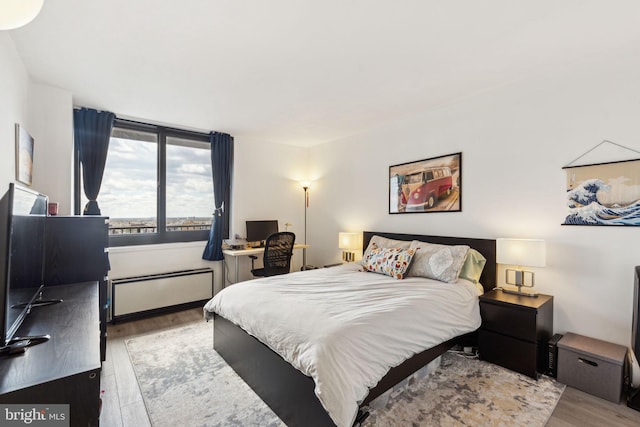 bedroom with radiator heating unit and wood finished floors