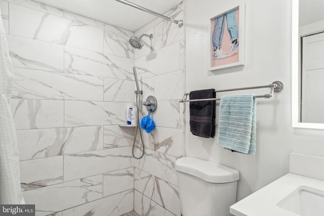 bathroom with a tile shower and toilet