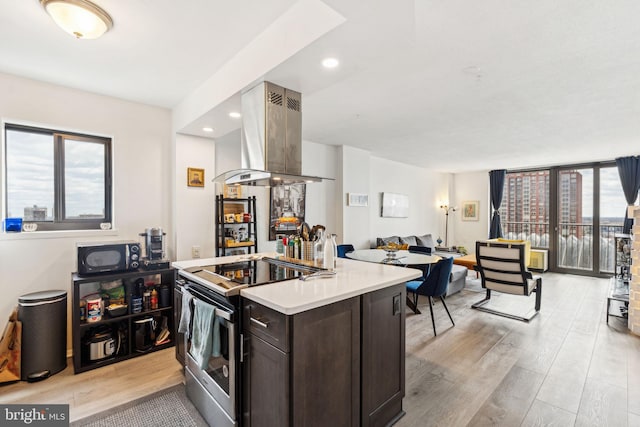 kitchen featuring dark brown cabinets, electric range, black microwave, island range hood, and light wood-type flooring