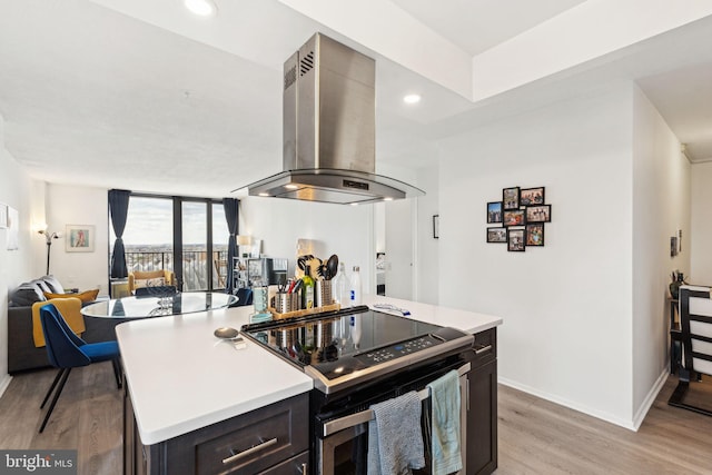 kitchen with ventilation hood, electric range oven, light countertops, light wood-style flooring, and baseboards