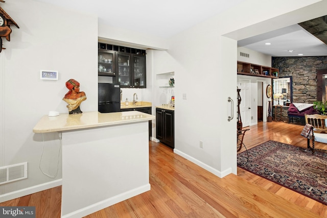 bar with wet bar, light wood finished floors, visible vents, and freestanding refrigerator