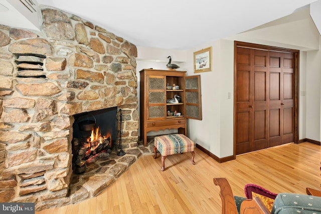 living area with baseboards, wood finished floors, and a fireplace
