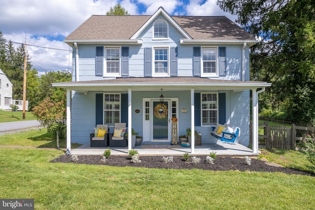 view of front of property featuring fence, covered porch, a shingled roof, and a front yard
