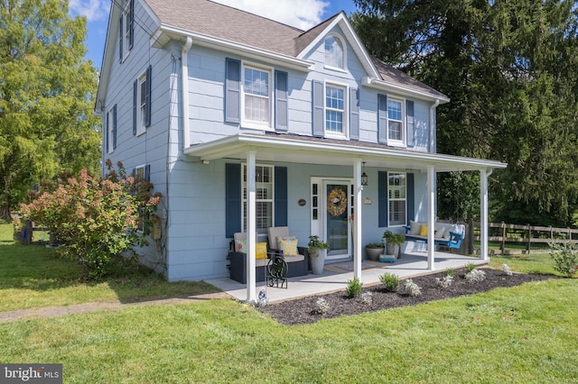view of front of property featuring a porch, fence, a shingled roof, and a front lawn