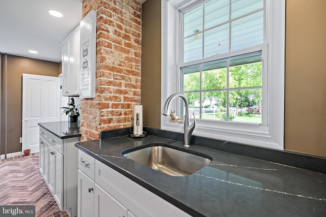 kitchen with white cabinetry, recessed lighting, a sink, and dark stone countertops
