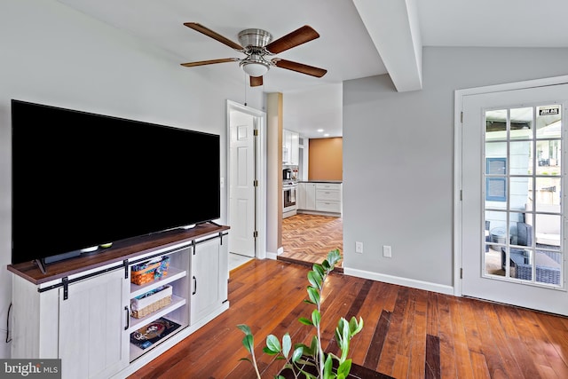 unfurnished living room featuring a ceiling fan, baseboards, vaulted ceiling, and dark wood-type flooring