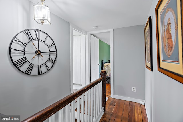 hallway with baseboards, dark wood-style flooring, and an upstairs landing