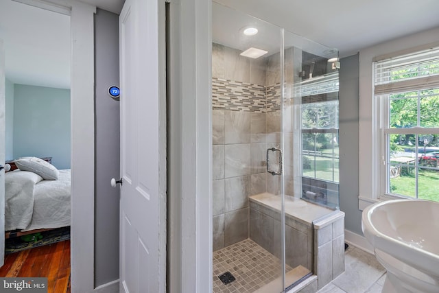 ensuite bathroom with a healthy amount of sunlight, baseboards, a stall shower, and ensuite bath