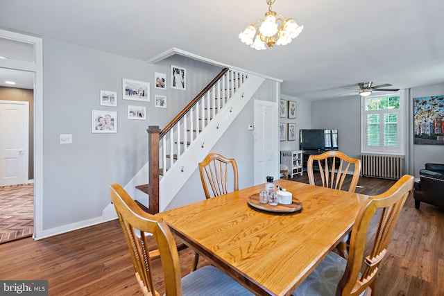 dining area featuring radiator heating unit, stairway, ceiling fan with notable chandelier, and wood finished floors
