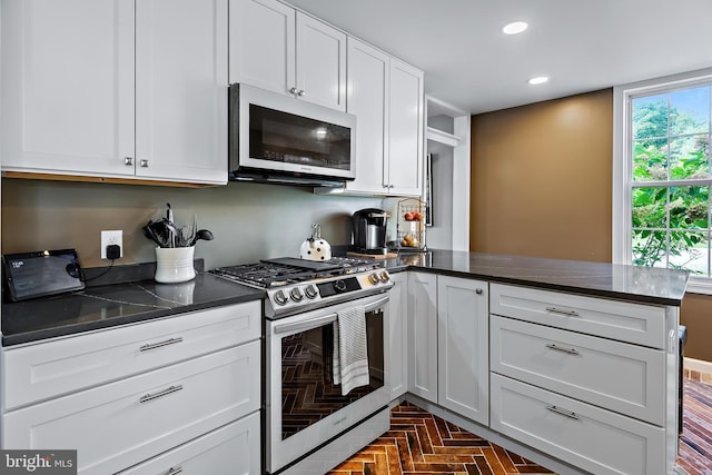 kitchen with white cabinets, stainless steel range with gas stovetop, a peninsula, recessed lighting, and white microwave