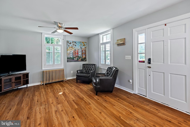 foyer featuring a ceiling fan, a wealth of natural light, wood finished floors, and radiator