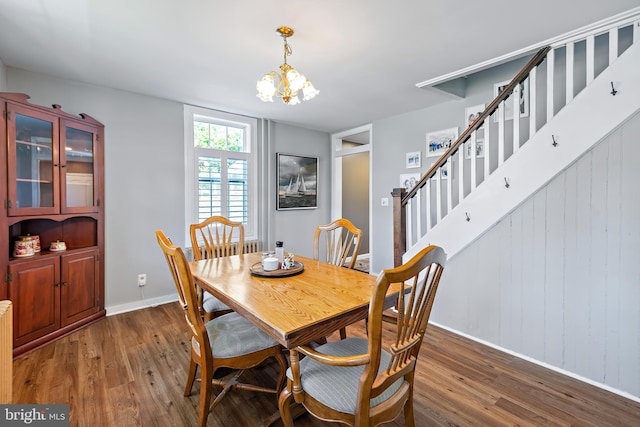 dining area featuring baseboards, stairs, wood finished floors, and a notable chandelier
