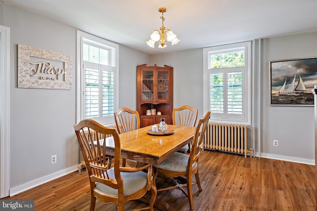 dining space featuring a healthy amount of sunlight, an inviting chandelier, wood finished floors, baseboards, and radiator heating unit