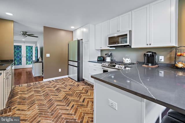 kitchen with recessed lighting, brick floor, dark countertops, and stainless steel appliances
