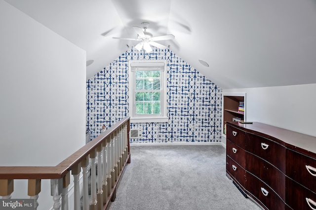 interior space featuring lofted ceiling, baseboards, ceiling fan, wallpapered walls, and carpet flooring