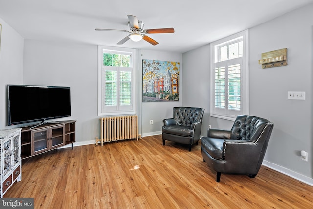 living area with light wood-style flooring, ceiling fan, radiator heating unit, and a wealth of natural light