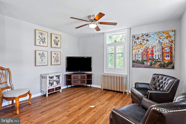 sitting room with radiator heating unit, baseboards, a ceiling fan, and light wood finished floors