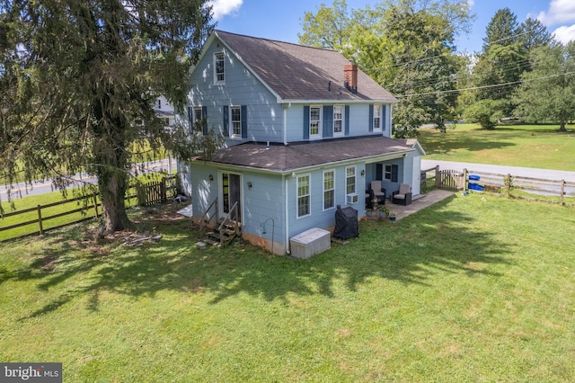 rear view of property featuring a chimney, a fenced backyard, a yard, a shingled roof, and entry steps