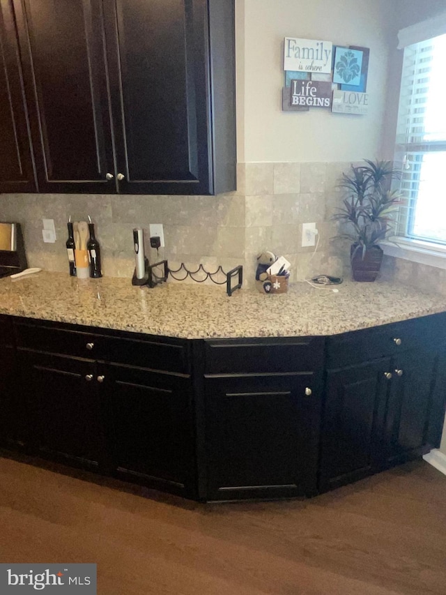 7805 Wistar Woods Pl, Henrico, VA 23228 - kitchen featuring light stone counters, dark cabinets, backsplash, and wood finished floors