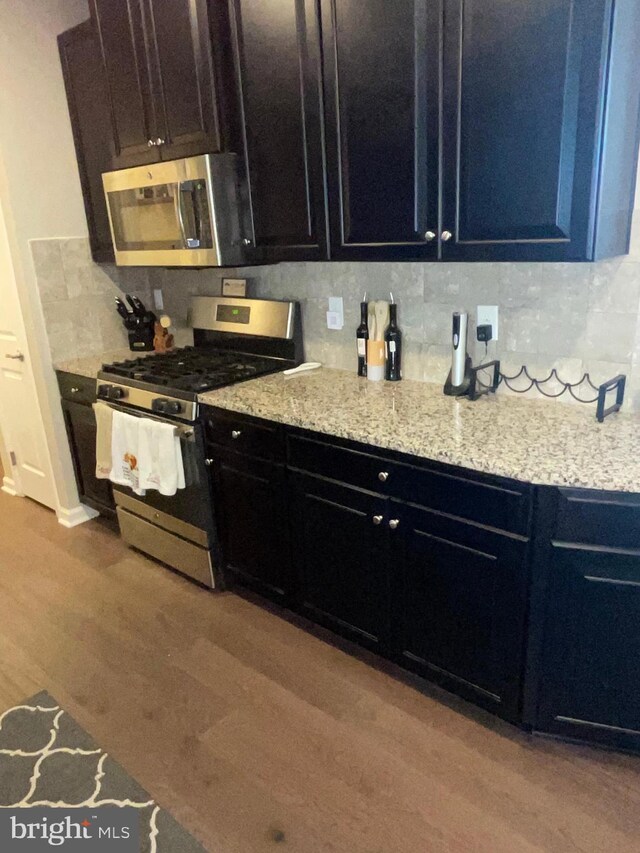 7805 Wistar Woods Pl, Henrico, VA 23228 - kitchen with dark cabinets, appliances with stainless steel finishes, wood finished floors, and decorative backsplash