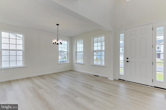 foyer with light wood-style flooring, baseboards, and a notable chandelier