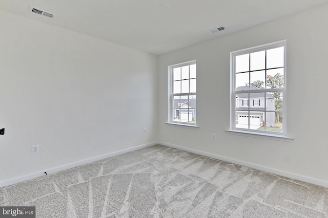 empty room with carpet, visible vents, and baseboards