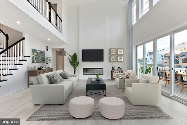 living room featuring visible vents, wood finished floors, a towering ceiling, and stairs