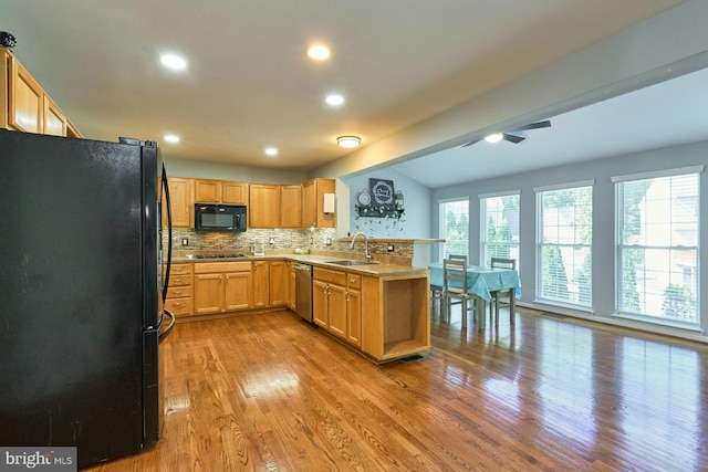 kitchen with a peninsula, recessed lighting, wood finished floors, tasteful backsplash, and black appliances
