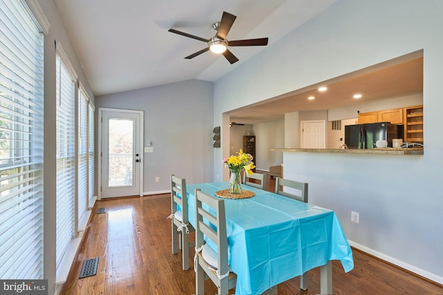 dining area featuring a ceiling fan, visible vents, vaulted ceiling, wood finished floors, and baseboards