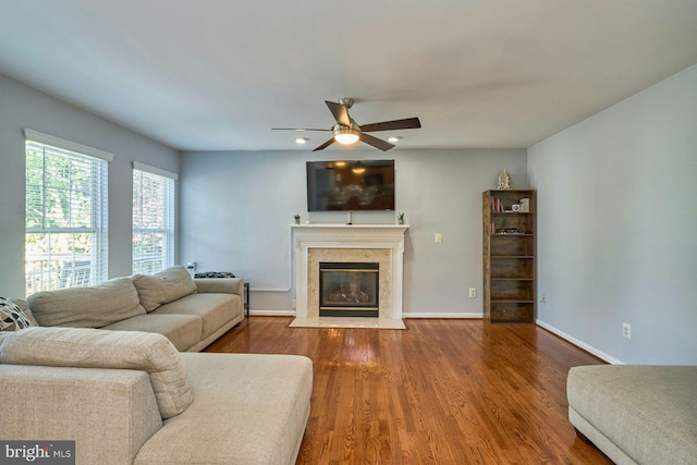 living room featuring a ceiling fan, baseboards, wood finished floors, and a fireplace